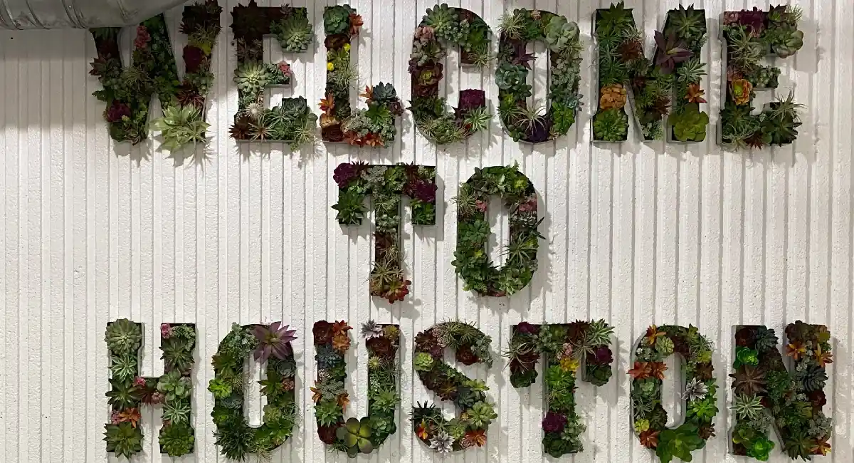Green wall that spells out Welcome to Houston