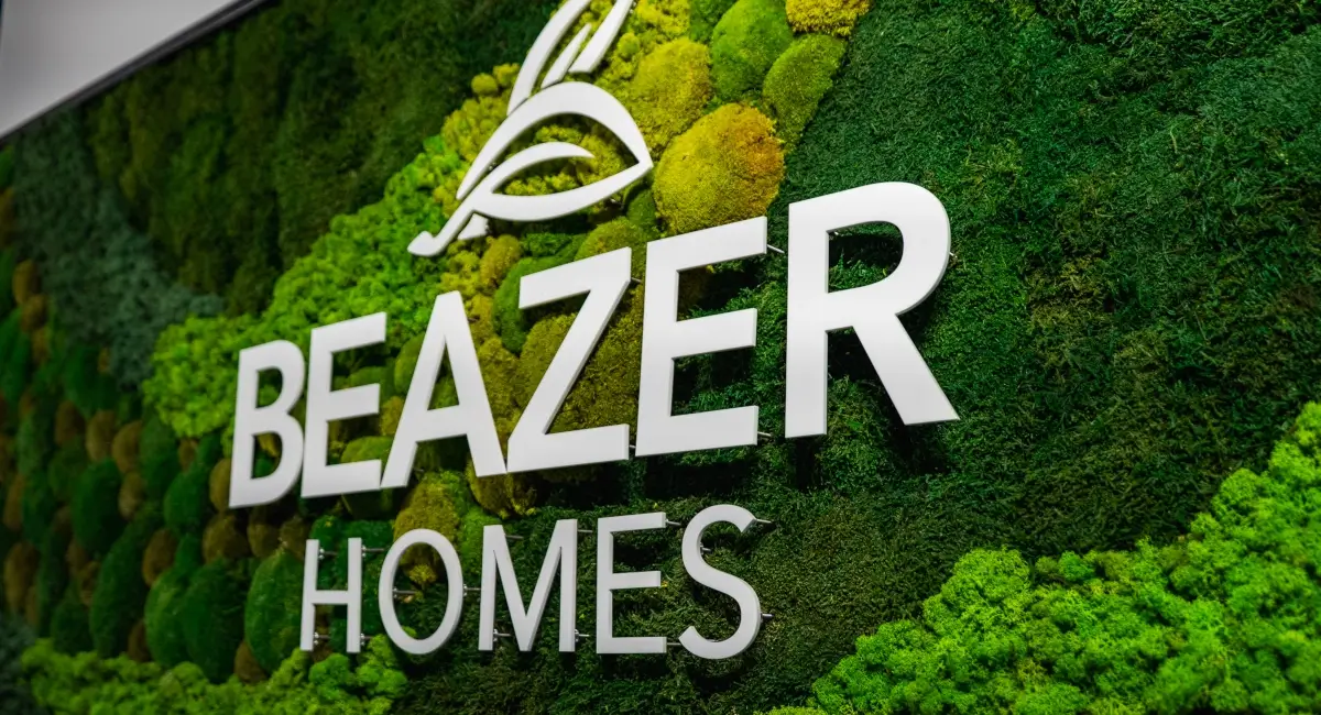 Close-up of a white 3D Beazer Homes logo mounted on a vibrant, preserved moss art installation.