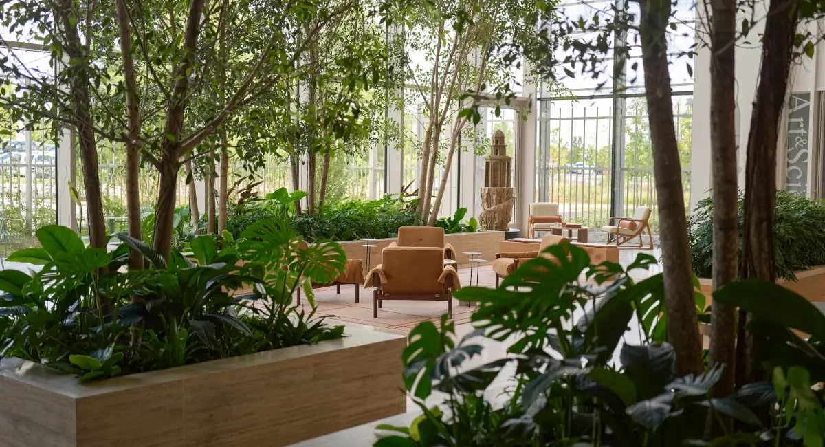 Comfortable lounge seating area in a biophilic office design surrounded by floor-to-ceiling windows and indoor greenery.