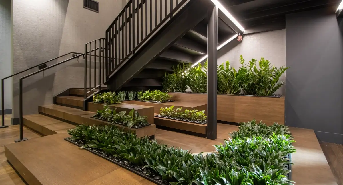 Modern staircase featuring built-in wooden planters with lush green indoor plants and integrated lighting.