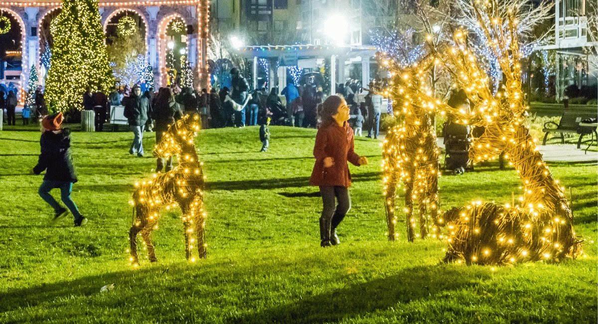 Children play with illuminated animal sculptures(reindeer) in the lawn area of the community Christmas event.