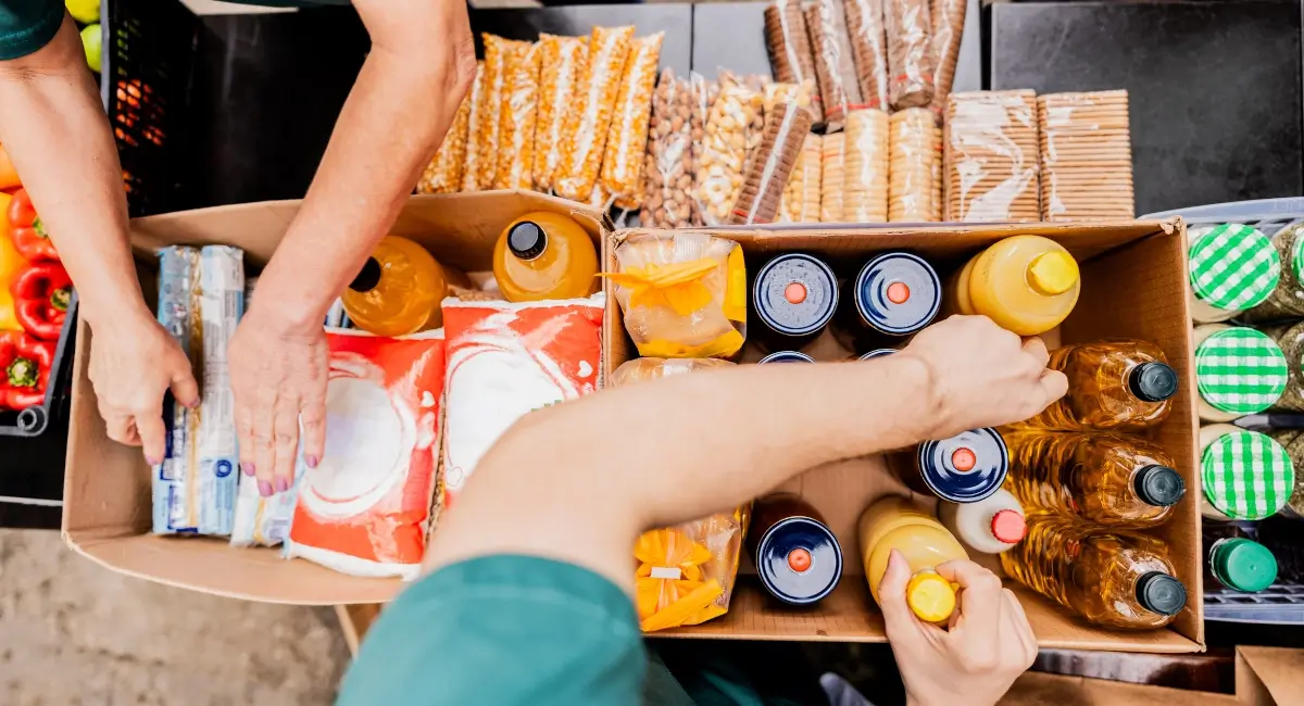 Stock image of people adding food items into cardboard boxes