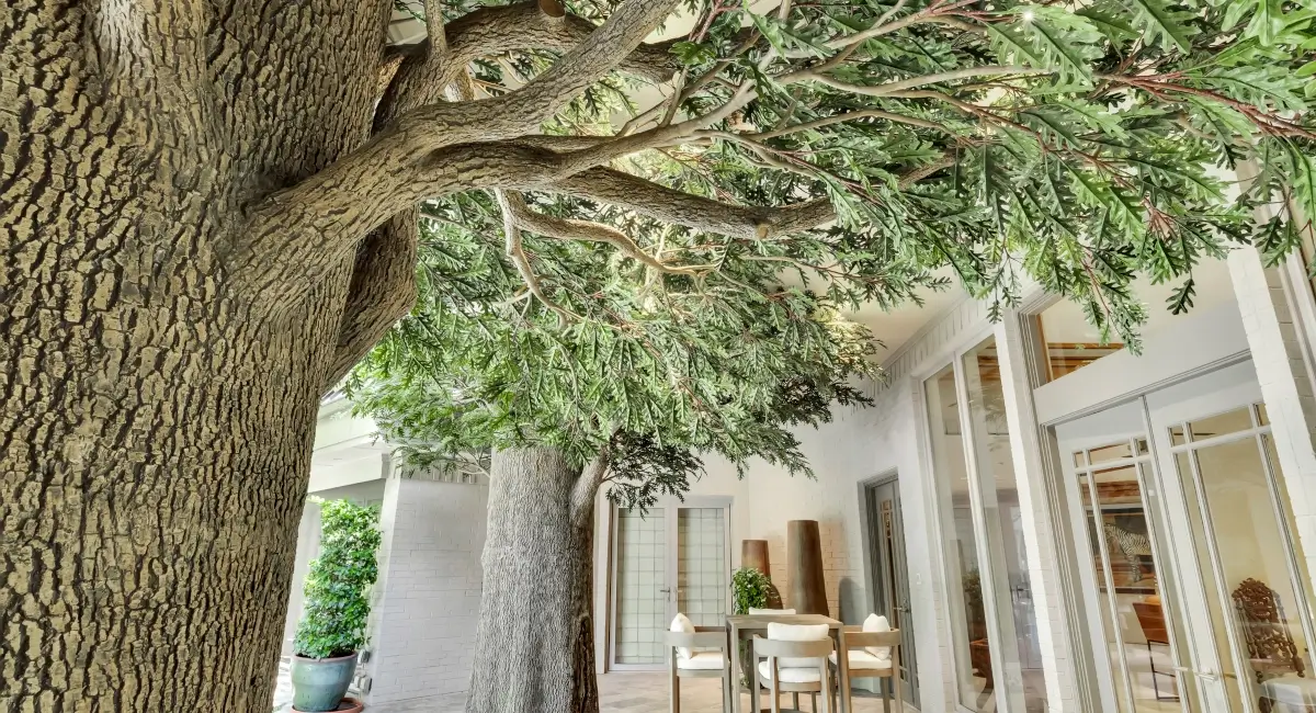 Detailed view of the realistic bark texture and green foliage of custom-built artificial trees in a residential courtyard.