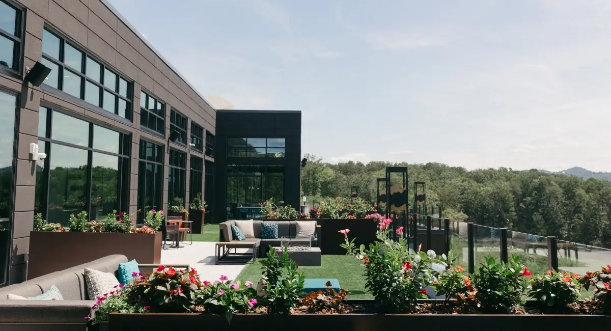 Expansive outdoor hotel terrace with modern furniture, artificial turf, and professional floral landscaping.
