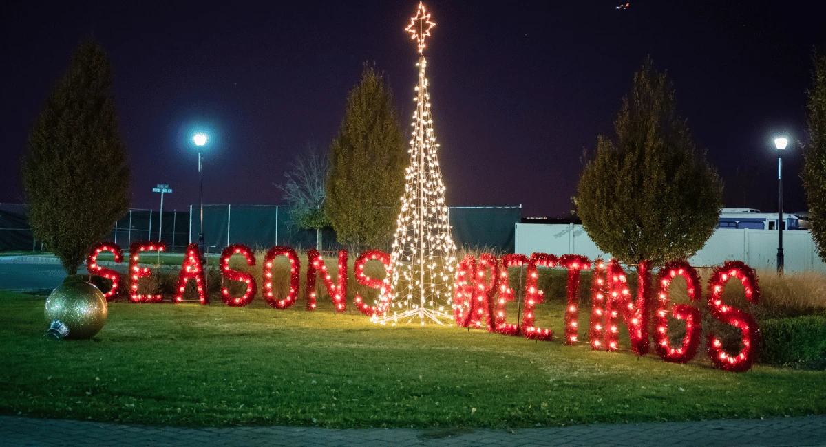 "Season's Greetings" holiday props with a lit Christmas tree in the center.