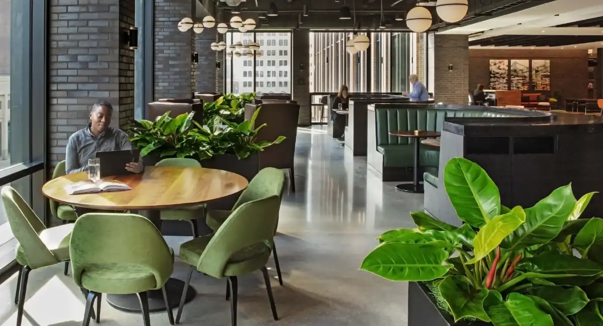 Office lounge with abundant greenery, seating areas, and employees working in a welcoming environment.