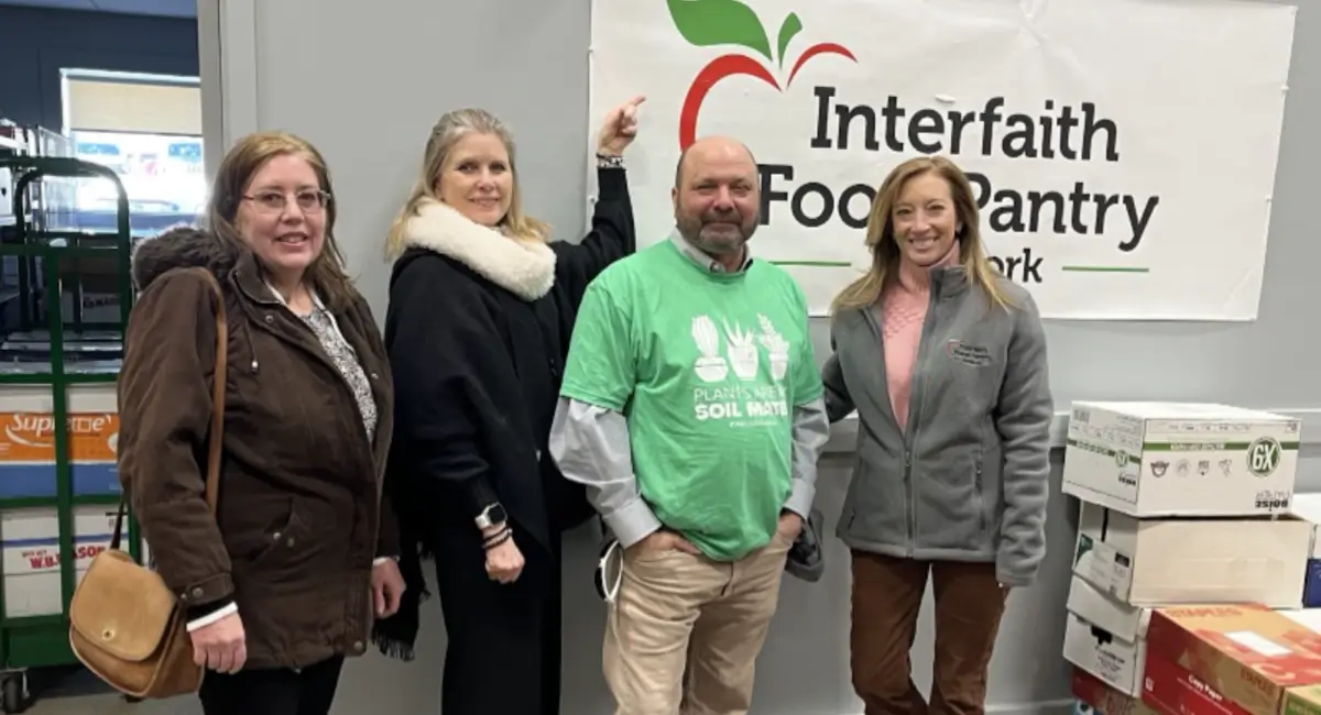 Four Ambius colleagues in front of Interfaith Food Pantry sign