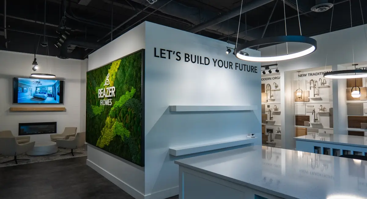 Modern interior of a Beazer Homes design center featuring a moss wall and "Let's Build Your Future" signage.