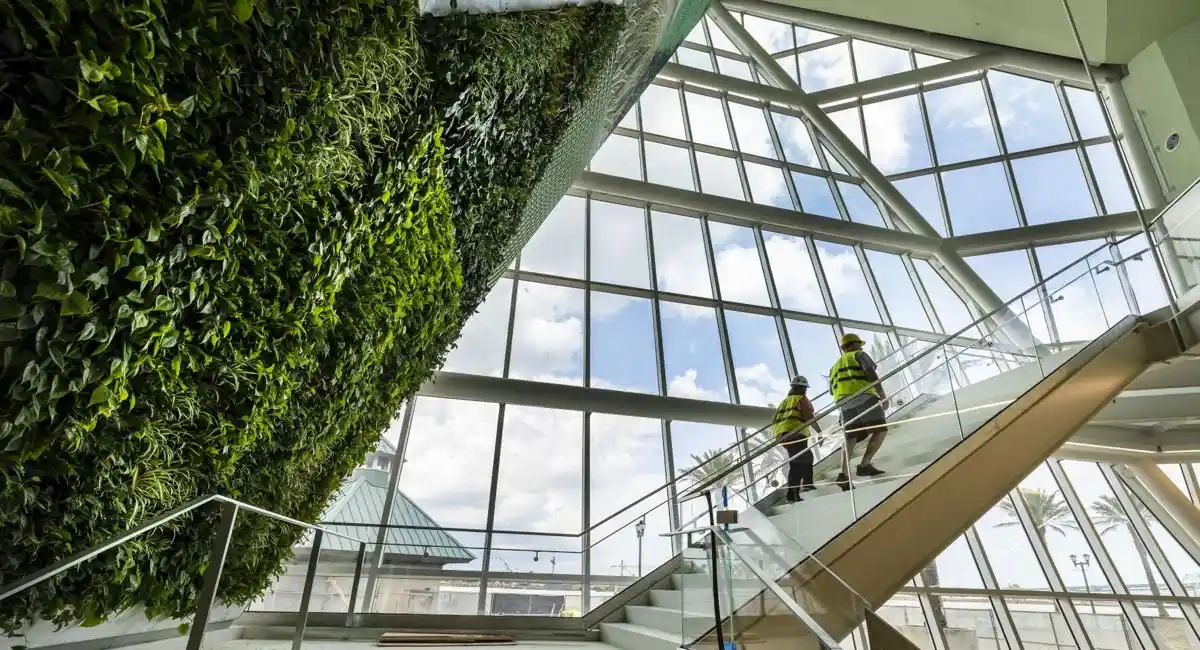two workers are walking up stair in a building by a living green wall