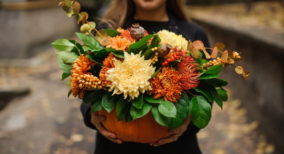 image-banner-stock-woman-holding-a-pumpkin-with-autumn-flowers-1008908718.webp