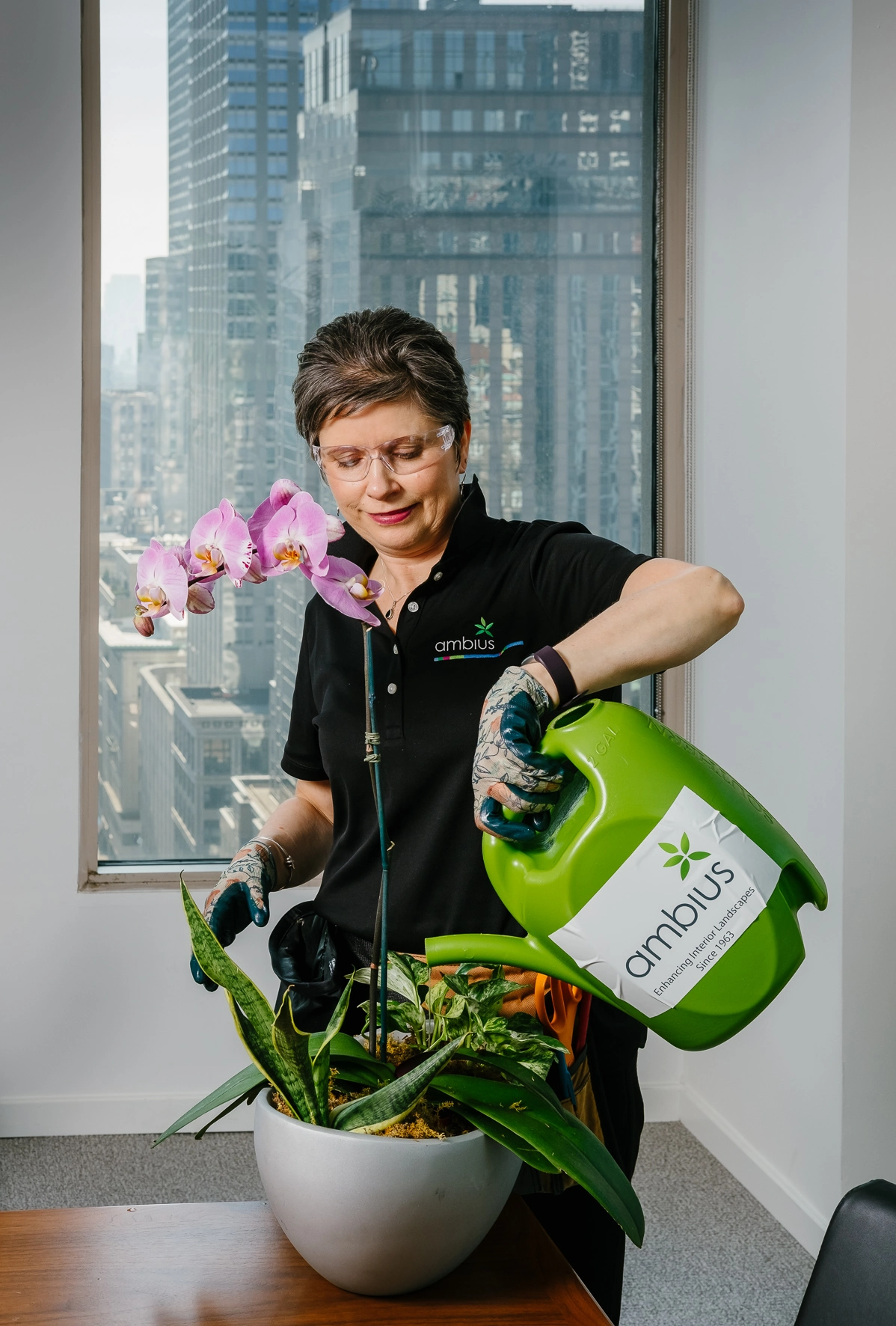 Woman watering floral design with Ambius watering can